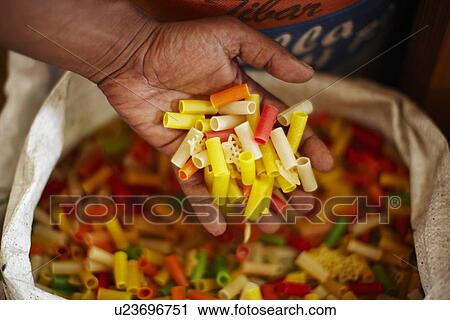 Stock Image - Close up of hand holding dried pasta. Fotosearch