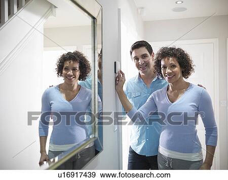 Stock Photo - Couple adjusting thermostat in home. Fotosearch