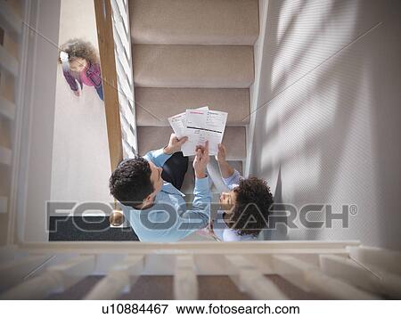 Couple arguing about bills on staircase View Large Photo Image Stock Photo - Couple arguing about bills on staircase. Fotosearch