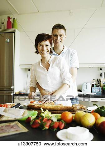 Stock Image - Couple cooking together in kitchen. Fotosearch