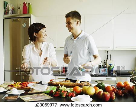 Couple cooking together in kitchen View Large Photo Image Stock Photo - Couple cooking together in kitchen. Fotosearch