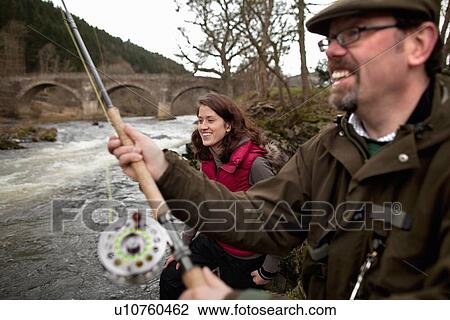 Stock Image - Couple fishing for salmon in river. Fotosearch