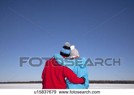 Couple hugging in snowy field View Large Photo Image Stock Photo - Couple hugging in snowy field. Fotosearch