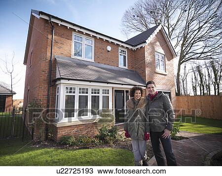 Stock Image - Couple smiling outside house. Fotosearch