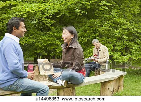 Couple talking on wooden bench in park View Large Photo Image Stock Image - Couple talking on wooden bench in park. Fotosearch