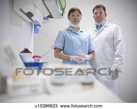 Stock Image - Dental student and dentist in surgery. Fotosearch