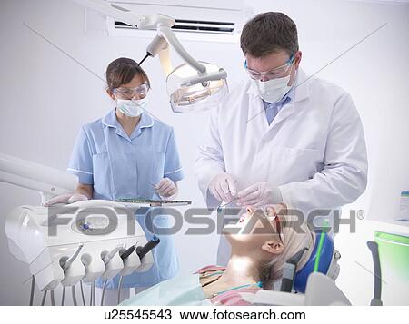 Stock Image - Dental student and dentist in surgery. Fotosearch