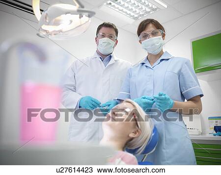 Stock Image - Dental student and dentist in surgery. Fotosearch