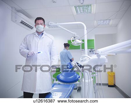 Dentist standing in examination room View Large Photo Image Stock Photo - Dentist standing in examination room. Fotosearch