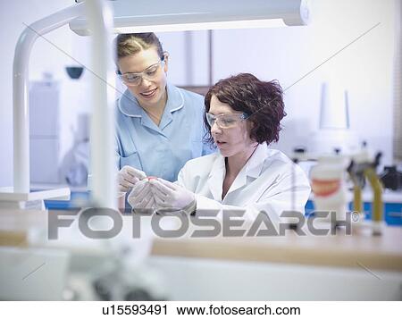 Stock Image - Dentist teaching student in lab. Fotosearch