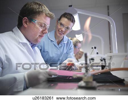 Stock Image - Dentist teaching students in lab. Fotosearch