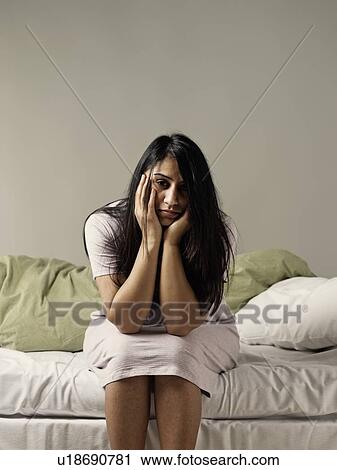 Stock Image - Depressed woman sitting on bed. Fotosearch