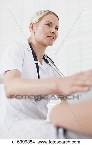 Picture - Doctor examining pregnant womans belly. Fotosearch