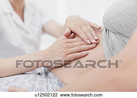 Doctor examining pregnant womans belly View Large Photo Image Stock Image - Doctor examining pregnant womans belly. Fotosearch