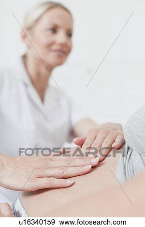 Stock Photo - Doctor examining pregnant womans belly. Fotosearch