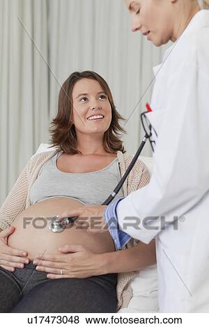 Doctor examining pregnant womans belly View Large Photo Image Stock Photo - Doctor examining pregnant womans belly. Fotosearch