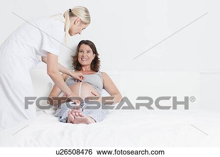 Doctor examining pregnant womans belly View Large Photo Image Stock Photograph - Doctor examining pregnant womans belly. Fotosearch
