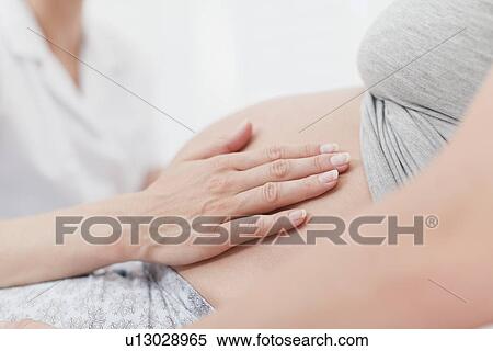 Stock Photography - Doctor examining pregnant womans belly. Fotosearch