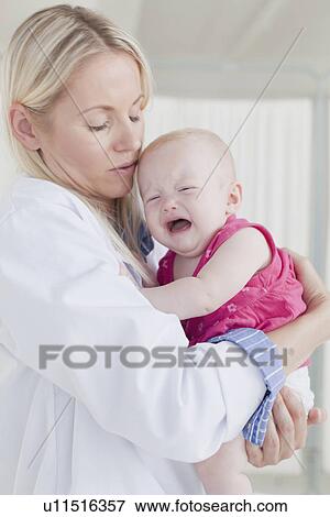 Stock Photo - Doctor hugging crying baby. Fotosearch