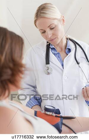 Doctor taking womans blood pressure View Large Photo Image Stock Image - Doctor taking womans blood pressure. Fotosearch