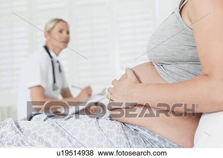 Stock Photo - Doctor talking to pregnant woman. Fotosearch