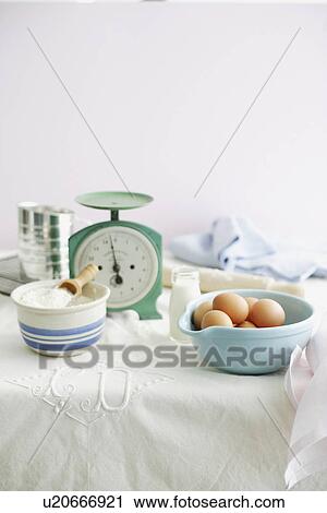 Stock Image - Eggs, flour, milk and scales in kitchen. Fotosearch