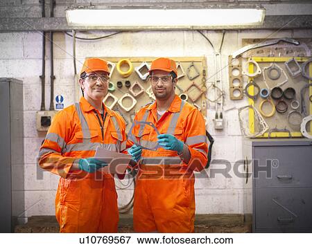 Stock Photo - Engineer teaching apprentice in factory. Fotosearch