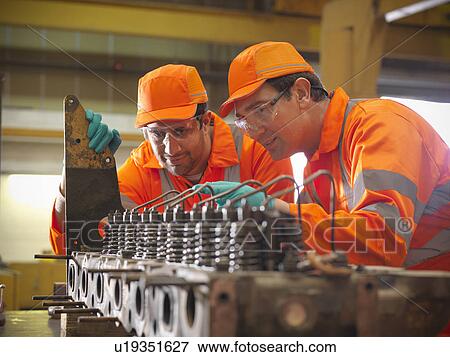 Stock Photo - Engineer teaching apprentice in factory. Fotosearch