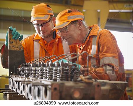 Stock Photo - Engineer teaching apprentice in factory. Fotosearch