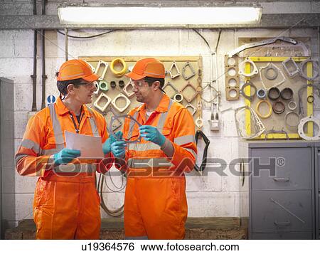 Stock Photograph - Engineer teaching apprentice in factory. Fotosearch
