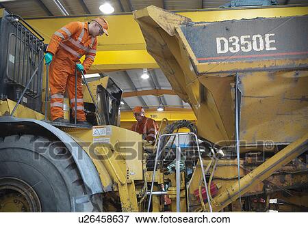 Stock Photo - Engineer teaching apprentice on truck. Fotosearch
