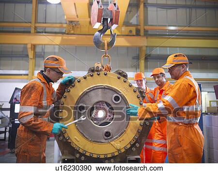 Stock Image - Engineer teaching apprentices in factory. Fotosearch
