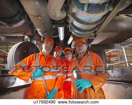 Stock Image - Engineer teaching apprentices in factory. Fotosearch