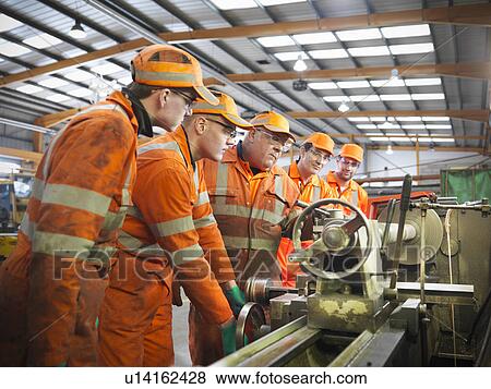 Stock Photo - Engineer teaching apprentices in factory. Fotosearch