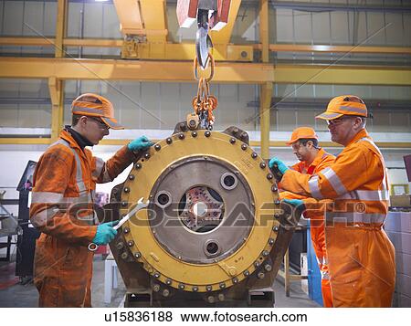 Stock Photo - Engineer teaching apprentices in factory. Fotosearch