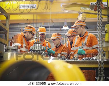 Stock Photography - Engineer teaching apprentices in factory. Fotosearch