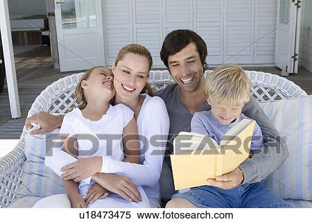 Stock Photography - Family reading on sofa together. Fotosearch