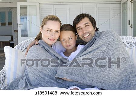 Family relaxing on sofa under blanket View Large Photo Image Stock Photo - Family relaxing on sofa under blanket. Fotosearch
