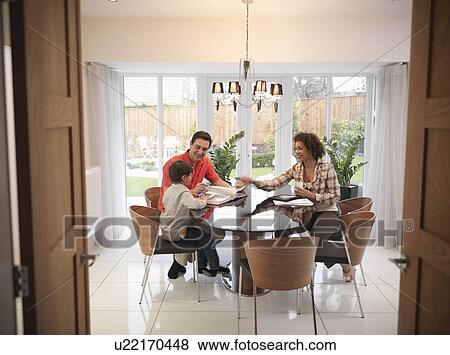 Stock Photo - Family relaxing together at dining table. Fotosearch