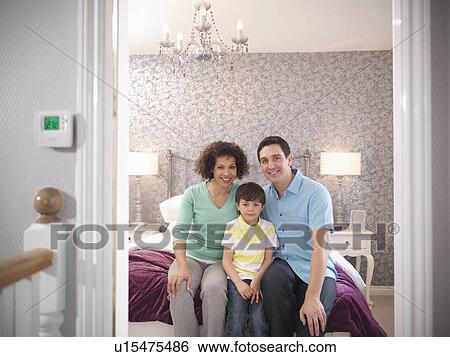 Stock Photograph - Family smiling together in bedroom. Fotosearch