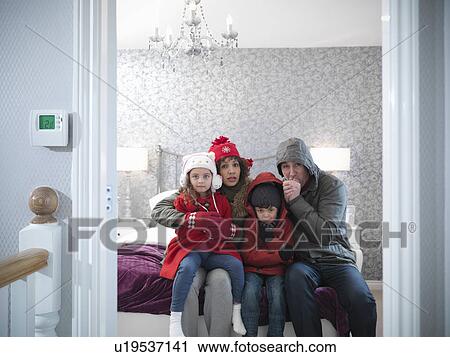 Stock Image - Family wearing snow gear in bedroom. Fotosearch