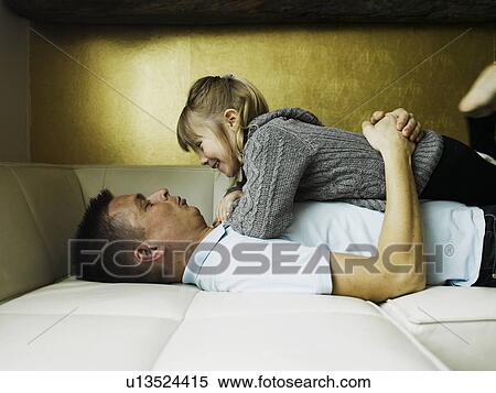 Stock Photography - Father and daughter relaxing on sofa. Fotosearch
