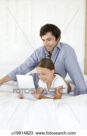 Stock Image - Father and daughter using tablet. Fotosearch