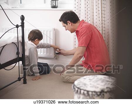 Stock Photograph - Father and son adjusting radiator. Fotosearch