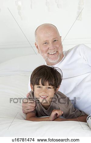 Picture - Father and son laying on bed. Fotosearch