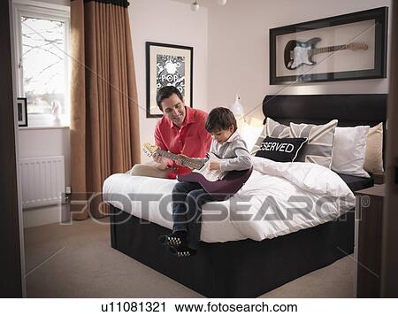 Father and son playing guitar in bedroom View Large Photo Image Stock Image - Father and son playing guitar in bedroom. Fotosearch