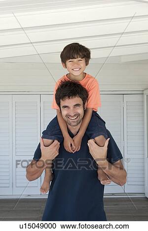 Stock Image - Father carrying son on shoulders. Fotosearch