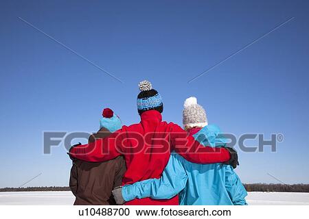 Stock Image - Friends hugging in snowy field. Fotosearch