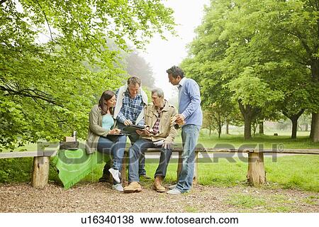 Friends using tablet computer in park View Large Photo Image Stock Photo - Friends using tablet computer in park. Fotosearch