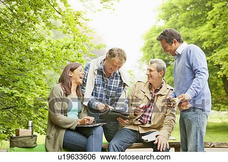 Friends using tablet computer in park View Large Photo Image Stock Photograph - Friends using tablet computer in park. Fotosearch